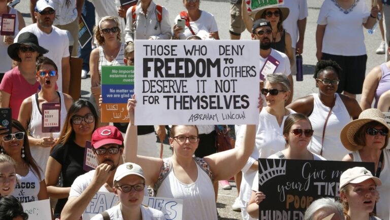 A large group of diverse individuals protesting, holding signs advocating for freedom and justice.