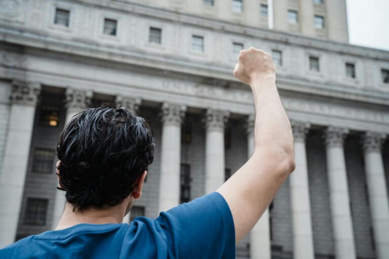 Man raising fist in protest against a historic building. Symbol of activism and empowerment.